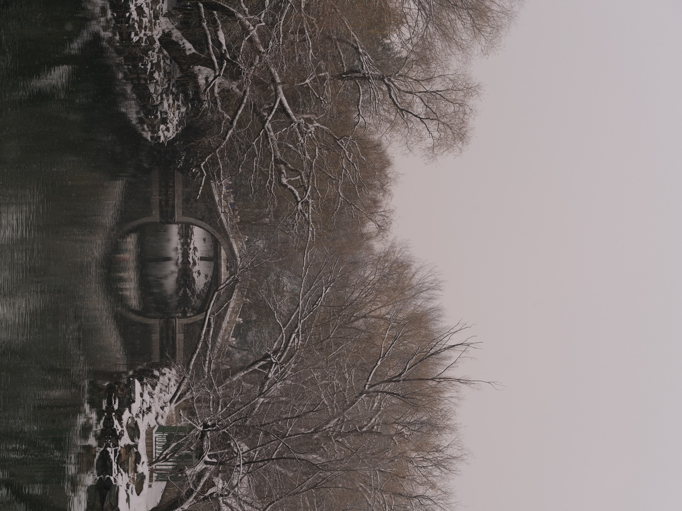 Snow-covered bridge reflected in still water